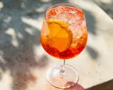 Ett glas Aperol Spritz med is och apelsinskiva, perfekt för en solig dag.