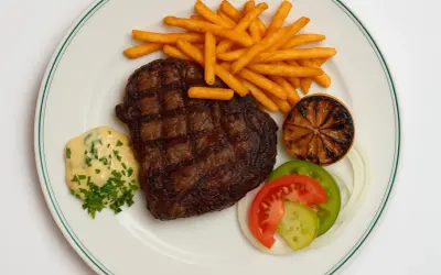 En saftig biff med pommes frites, bearnaisesås och grönsaker, en klassisk rätt från Brasserie Astoria.