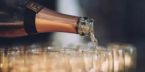 En flaska hälls upp i glas, det ser ut att bli gott bubbel.