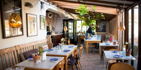 Mysig vinterträdgård med rustika bänkar och marmorbord, en av många annorlunda restauranger i Skåne.