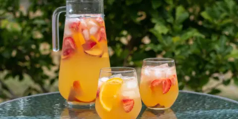 En karaff och två glas med en uppfriskande cava drink fylld med is, jordgubbar och apelsinskivor. Perfekt för en sommardag.