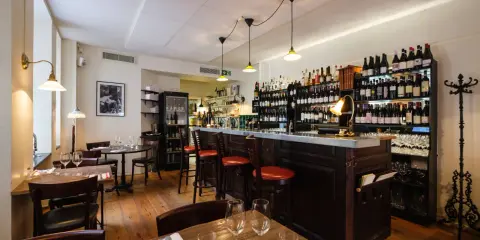 Mysig vinbar med trägolv, bardisk och hyllor fyllda med flaskor. Perfekt för att läsa bouchon recensioner över ett glas vin.