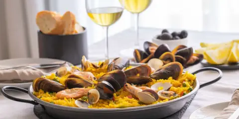 En härlig paella med skaldjur och ris, perfekt att avnjuta med ett glas vitt vin till paella. Serveras med citronklyftor och oliver.