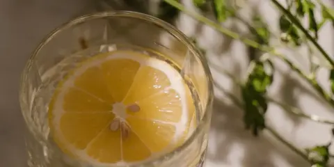Ett glas med vatten och en citronskiva, perfekt för varma sommardagar. Enkel och uppfriskande bland sommar drinkar.