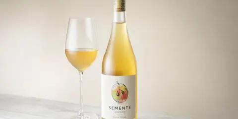 En flaska och ett glas med gyllene Semente Avesso vin.