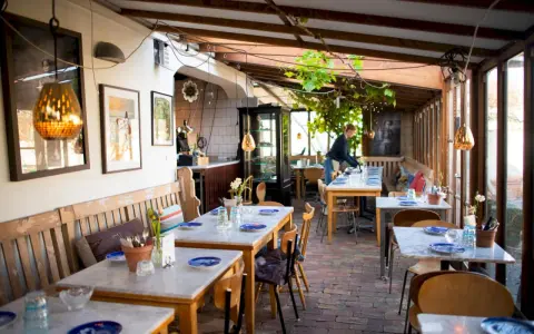 Mysig vinterträdgård med rustika bänkar och marmorbord, en av många annorlunda restauranger i Skåne.