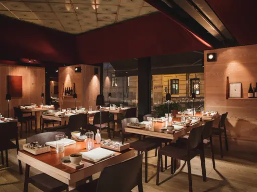 Elegant inredning på en michelin restaurang i Sverige. Vackert dukade bord med trädetaljer och dämpad belysning skapar en intim atmosfär.