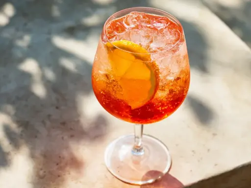 Ett glas Aperol Spritz med is och apelsinskiva, perfekt för en solig dag.