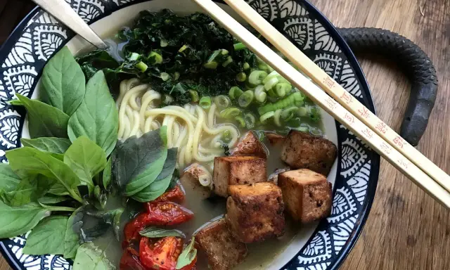En skål med vegetarisk ramen med nudlar, tofu, grönsaker och basilika.