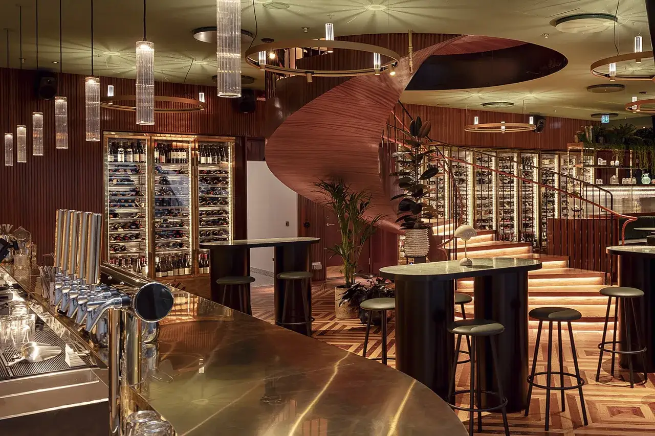 Elegant brasserie Astoria med en svängd trappa, vinväggar och en glänsande bardisk.