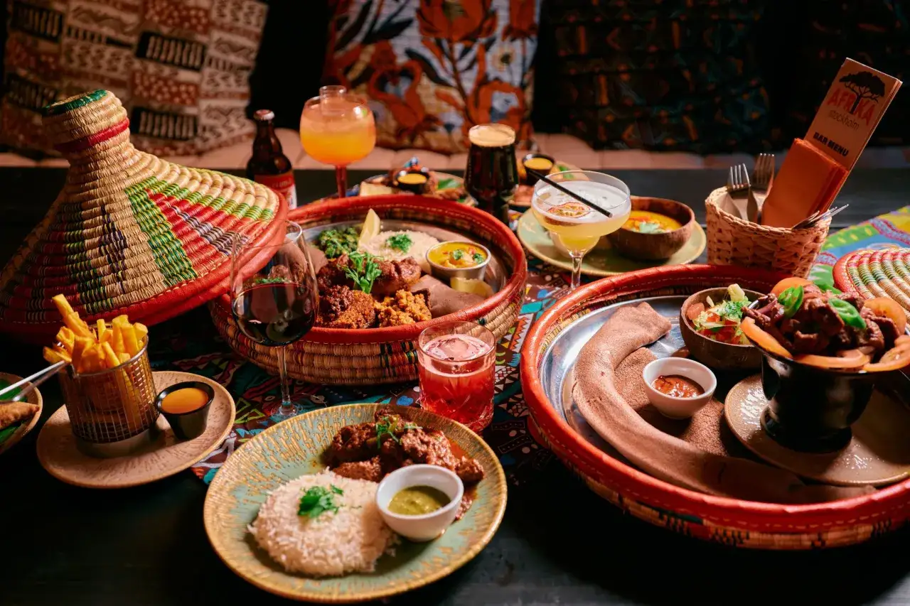 En h&auml;rlig m&aring;ltid p&aring; en afrikansk restaurang med flera r&auml;tter, drycker och en f&auml;rgglad duk.