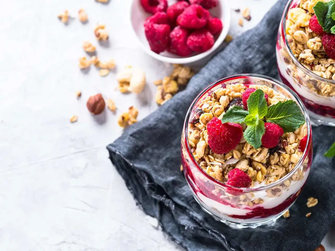 En läcker dessert i glas med yoghurt, hallon och granola. Perfekt för en hälsosam frukost eller mellanmål.