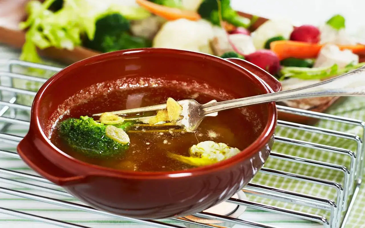 En sk&aring;l med varm buljong och gr&ouml;nsaker, som broccoli och blomk&aring;l, med en gaffel i. En h&auml;rlig bagna cauda-inspirerad r&auml;tt.