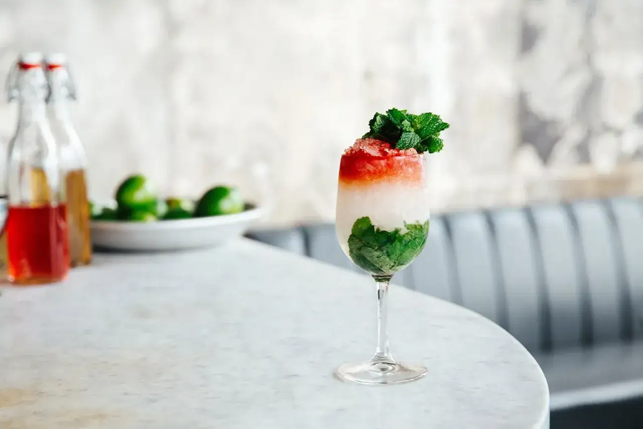 El Presidente cocktail med lager av mynta, is och röd topping, garnerad med mynta.