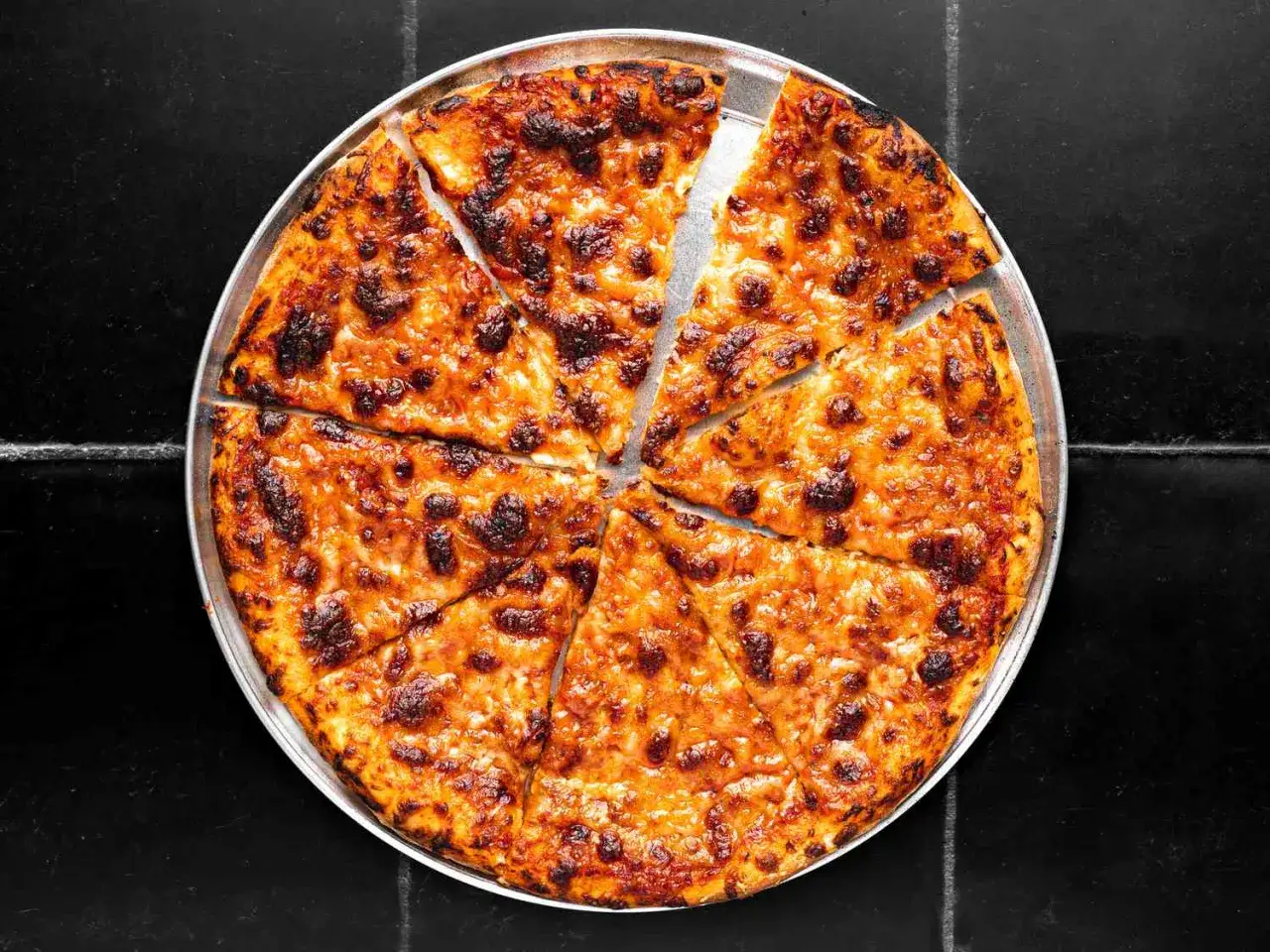 En gyllene, hemmagjord pizza med bubblig ost och lätt brända kanter, skuren i åtta bitar.