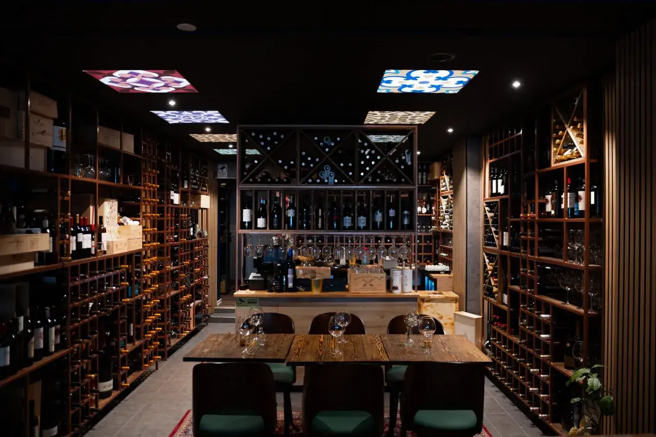 En vinbar med hyllor fyllda med flaskor, redo f&ouml;r en kv&auml;ll med pasion tapas och goda viner.