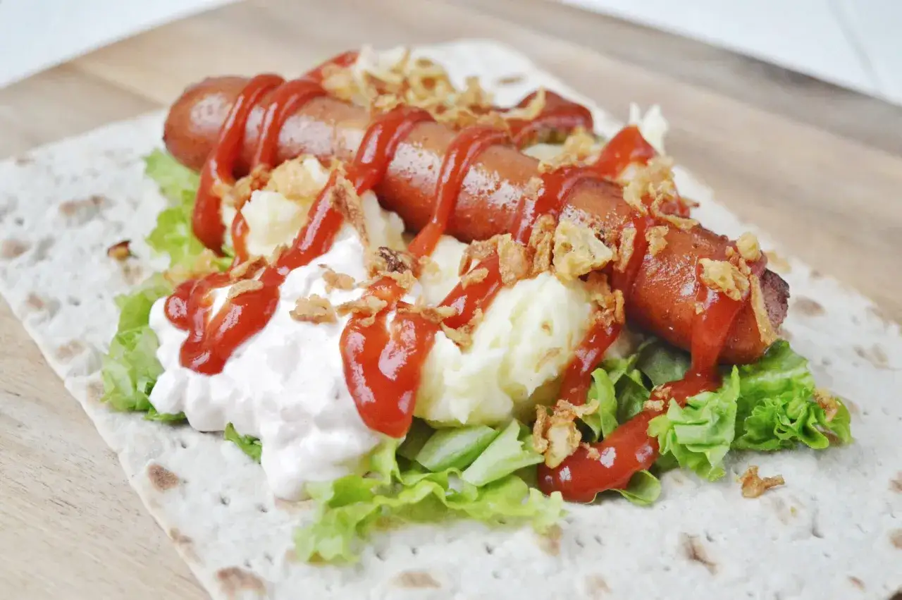 En svensk korv med mos, sallad, ketchup och friterad l&ouml;k p&aring; ett tunnbr&ouml;d. En riktig klassiker!