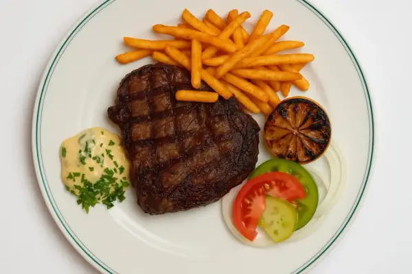 En saftig biff med pommes frites, bearnaisesås och grönsaker, en klassisk rätt från Brasserie Astoria.