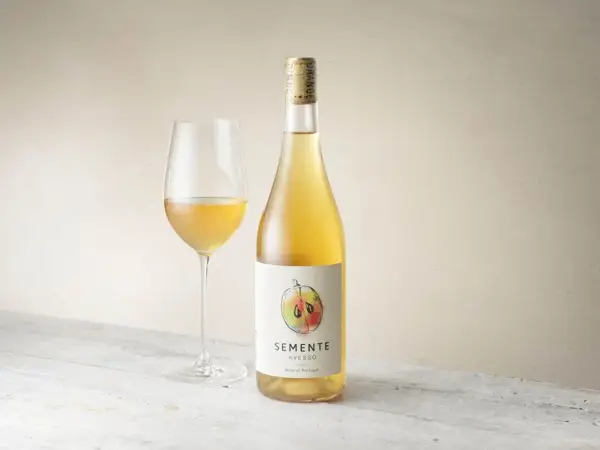 En flaska och ett glas med gyllene Semente Avesso vin.