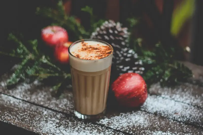 En krämig kaffedrink med kanel, omgiven av juliga äpplen och granris. Perfekt för mysiga stunder och inspirerar till egna kaffedrinkar recept.